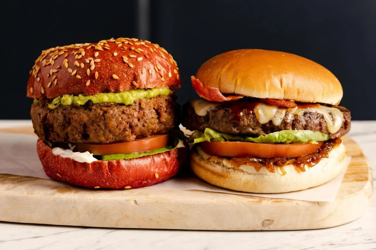 two hamburgers sitting on a wooden cutting board at Leonardo Hotel Aberdeen in Aberdeen